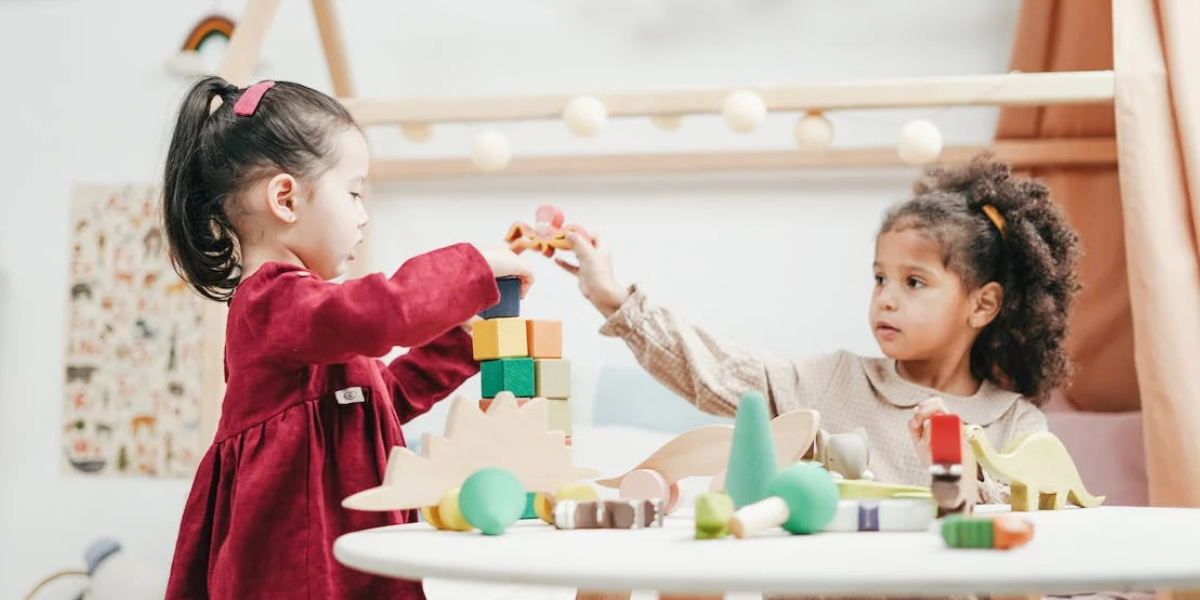 Two young girls playing with blocks in the classroom