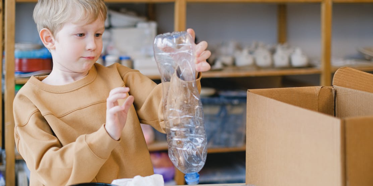 Young boy sorting plastic bottle for recycling