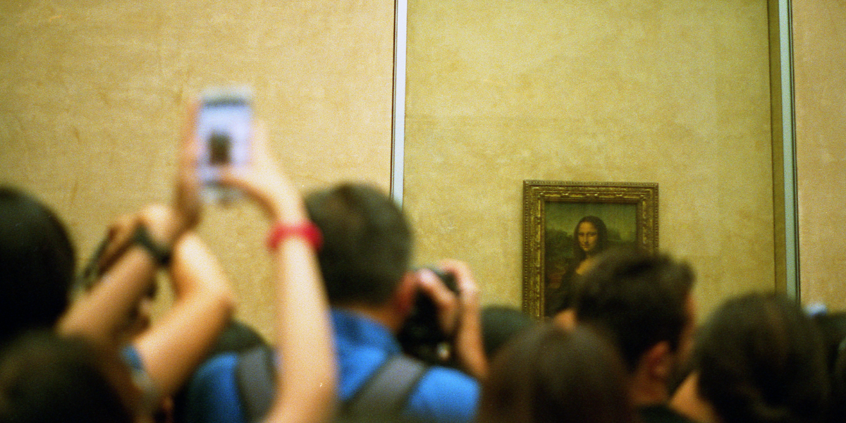 Person in art museum taking picture of Mona Lisa with smartphone